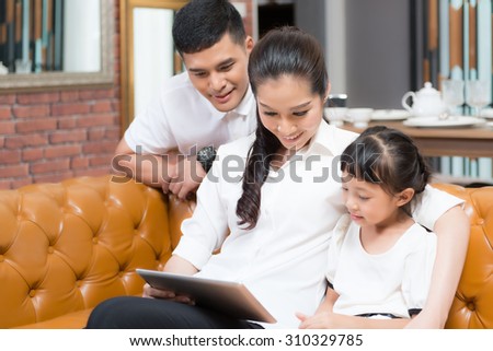 Asia Family Using Laptop Whilst Relaxing On Sofa At Home
