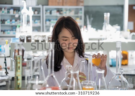 An Asia scientific researcher holding at a liquid solution in a lab.