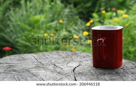 Red mug coffee on wooden tabletop against blurred green