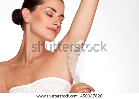 Armpit epilation, hair removal. Young woman holding her arms up and showing clean underarms, depilation smooth clear skin . Beauty portrait. armpit\'s care. Large white feather near  skin