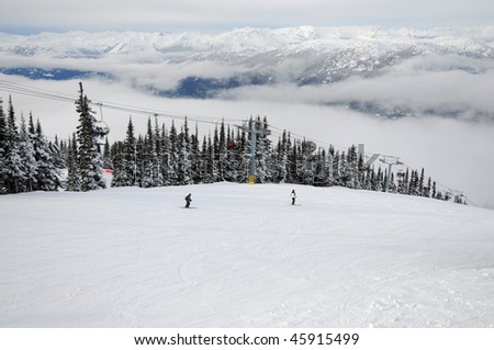 Two skiers sliding down the hill along a chairlift at Whistler-Blackcomb resort
