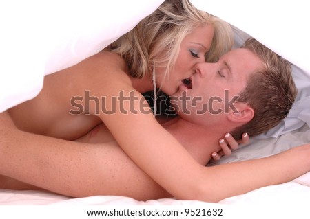 intimate couple in bed under white sheet engaged in steamy kiss implied sexual situation mouths open