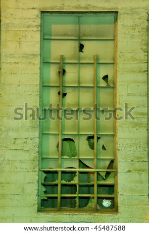 Old green window in run down warehouse with broken glass panes