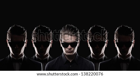 conceptual portrait of three solid young men in studio on dark background