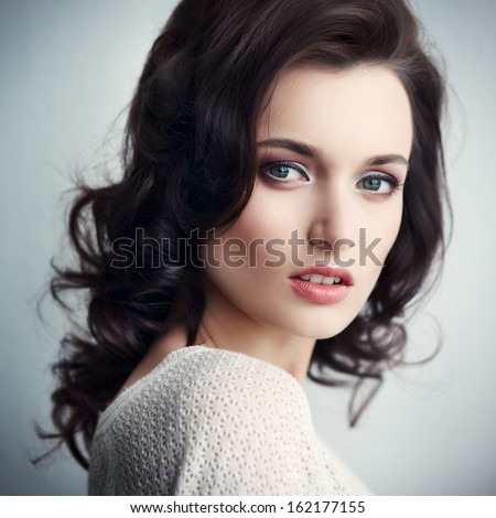 Portrait of the beautiful young fashionable girl in studio posing against a white wall