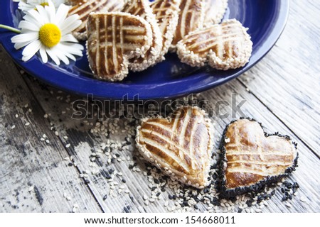 Cookies in the shape of heart on the table. Near a bouquet of daisies. Retro style. From the series 