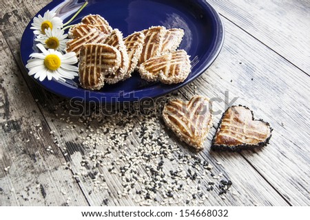 Cookies in the shape of heart on the table. Near a bouquet of daisies. Retro style. From the series \