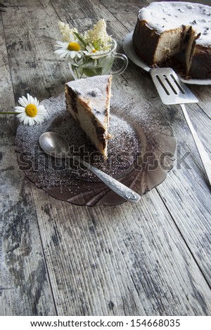 Cheesecake on an old table with a bouquet of daisies and a form for baking. Retro style. From the series \
