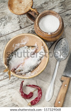 Two roaches fish in ceramic bowl with salt., near the old cutlery. From the series 