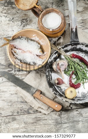 Two roaches fish in ceramic bowl with salt, near the old cutlery. From the series 