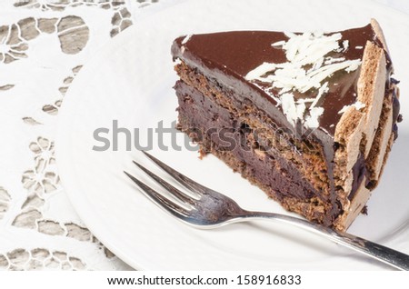 Slice of chocolate cake decorated with white chocolate flakes. From the series \