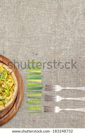 Pie quiche with leeks, cheese and sour cream on rough linen tablecloth Background for menu.