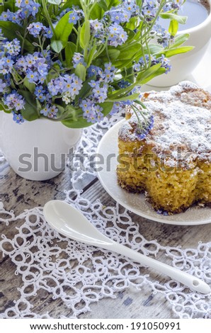 Polenta cake with cup of Coffee. Near forget me nots on rustic wooden table.