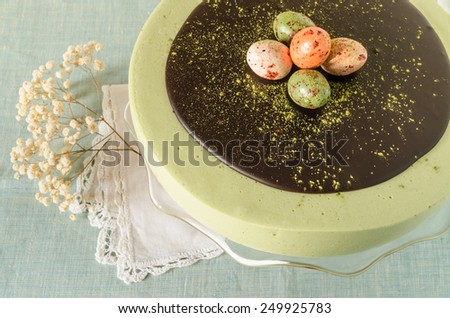 Easter cake with tea matcha decorated chocolate ganache and sweet-stuff eggs. Near cup of coffee.