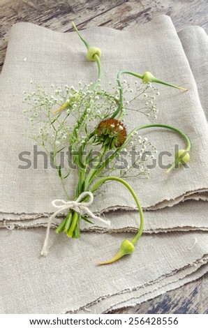 Still life with garlic buds and bouquet flowers on linen tablecloths Overhead view.