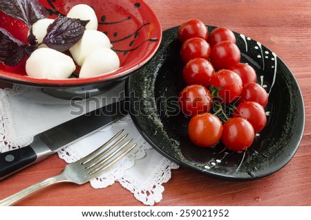 Ingredients for Italian caprese salad with fresh basil leaves, tomato and  mozzarella  on red wooden table. Overhead view. From series Natural organic food