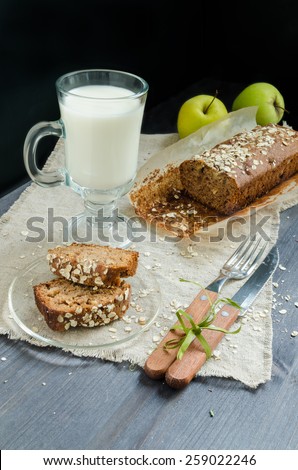 Homemade bread with apples in wrapping paper and glass of milk on white plate. From series of easy recipes