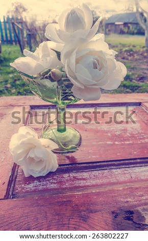 Beautiful bouquet of roses with drops in green glass vase on old wooden table. After the rain. Toned image. Selective focus. Rustic style.