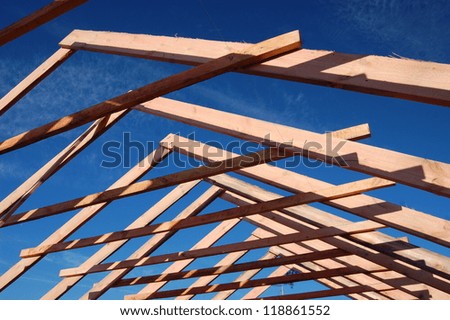 Wood Roof Trusses viewed from inside of new home looking out to a blue sky above .Ukraine