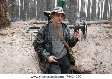Military archeology. Man with metal detector and Soviet 82-mm mortar shell remains on the battlefield of WW2.