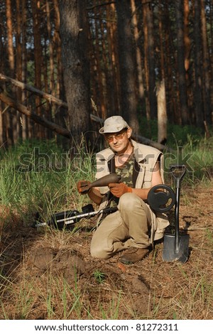 Military archeology. Man with metal detector and Soviet WWII 82-mm mortar-shell. Eastern Europe