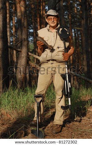 Military archeology. Man with metal detector and Soviet WWII 82-mm mortar-shell. Eastern Europe