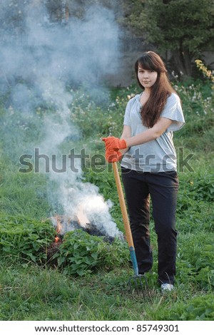 Teen girl burn out dry grass in the garden.Ukraine