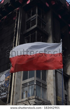KIEV, UKRAINE -MAR 24, 2014: Downtown of Kiev.Polish flag.Burnt down the House of trade unions as a background. Riot in Kiev and Western Ukraine.March 24, 2014 Kiev, Ukraine