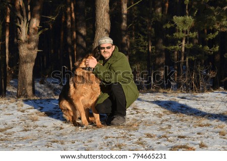 Man with dog wears traditional Kazakh hat in the forest