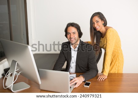 Business couple working at the computer looking at the camera
