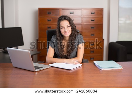 Woman executive on desk looking at camera