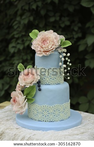 Wedding fondant flower cakes on the table with scarf, background is green leaf wall