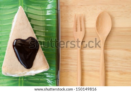 Crepe cake and heart shaped chocolate sauce, on banana leaf plate.
