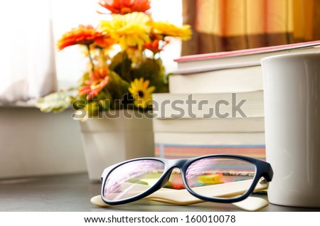 books and the glasses on table, near windows.