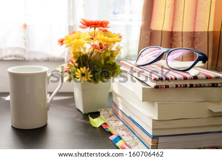 books and the glasses on table, near windows.