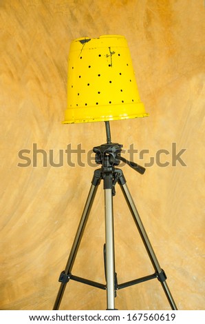 yellow floor lamp, D.I.Y by pot and tripods, isolated over vintage wall.