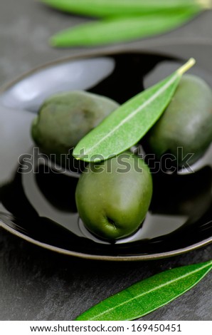 Green olives on black small plate