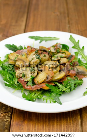 Appetizer with fresh rocket salad, smoked ham and fried mushrooms