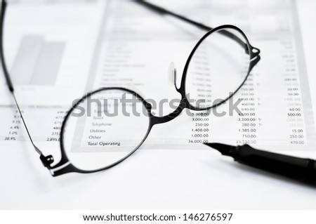 Balance sheet, eye glasses, and pen on the table