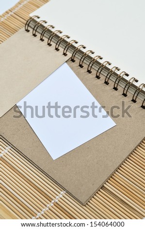 Blank notepad with a piece of paper on bamboo mat background