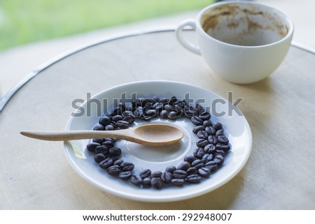 A cup of coffee on wooden table with Coffee beans and wooden spoon