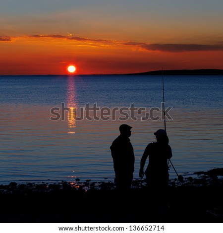 Two people fishing for flounder at sunset on the seashore
