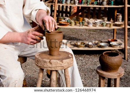 Potter in white clothes making a pot