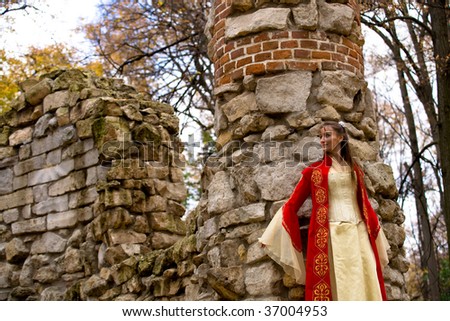 lady in medieval red dress standing near old wall