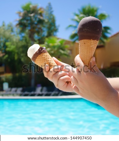 Ice cream in a child\'s hand close-up on the background of the swimming pool