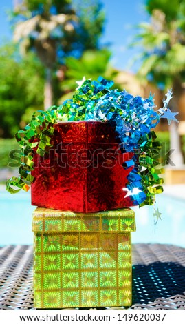 Red and gold gift boxes with ribbon by the swimming pool