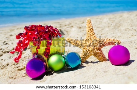 Starfish with gift box and christmas balls on the beach by the ocean - holiday concept