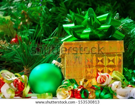 Golden Gift box with green bow and ball on the Christmas tree background