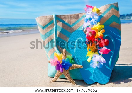 Beach bag with starfish and flip flops by the ocean