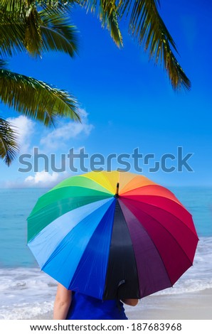 Girl with rainbow umbrella by the ocean